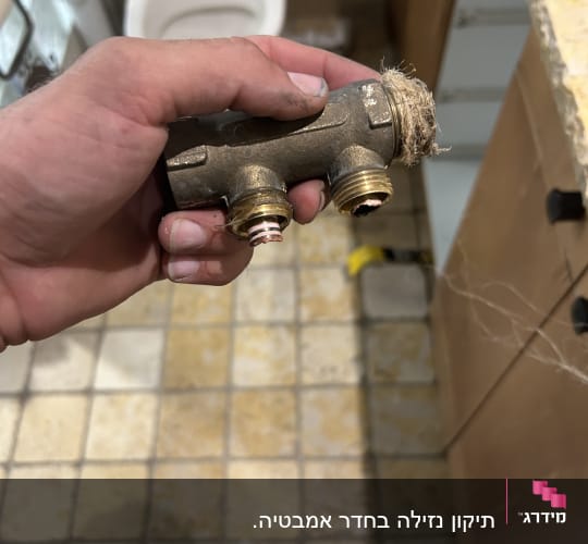 יד מחזיקה חלק אינסטלציה בחדר אמבטיה